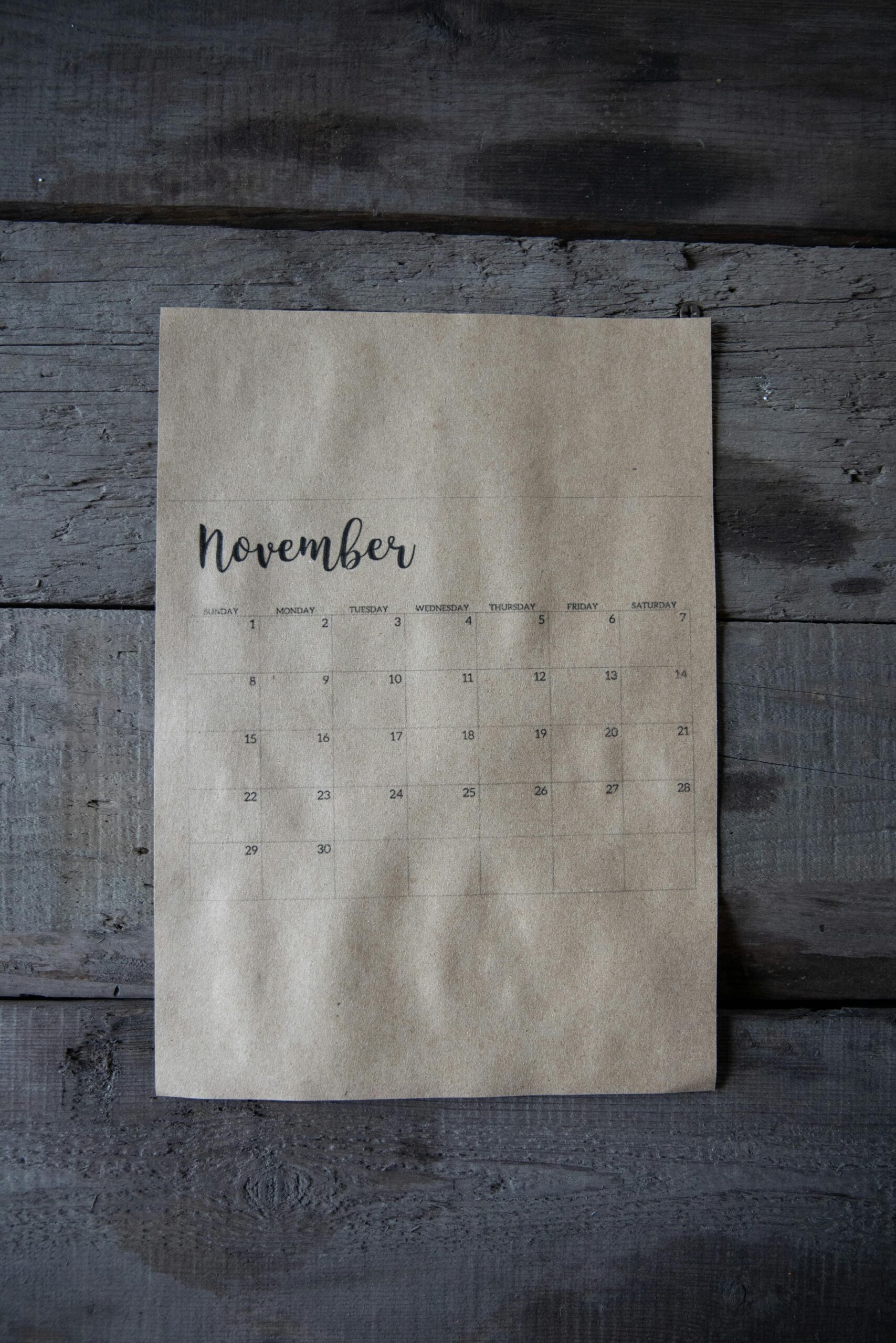 A vintage-style November calendar page on a rustic wooden background.